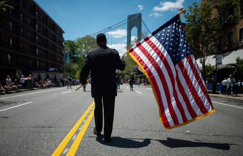 A veteran carries an American flag as he marches on the street May 27, 2019, during the 152nd Memorial Day parade in the New York City borough of Brooklyn.