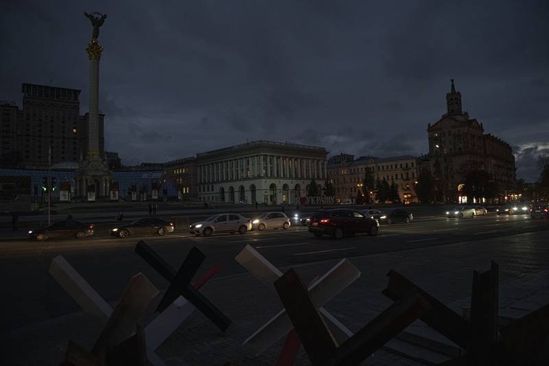 Cars pass in Independence Square at twilight in Kyiv, Ukraine, Monday, Oct. 31, 2022.