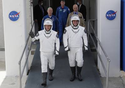 NASA astronauts Douglas Hurley, left, and Robert Behnken wave as they walk out of the Neil A. Armstrong Operations and Checkout Building on their way to Pad 39-A, at the Kennedy Space Center in Cape Canaveral, Fla., Wednesday, May 27, 2020.