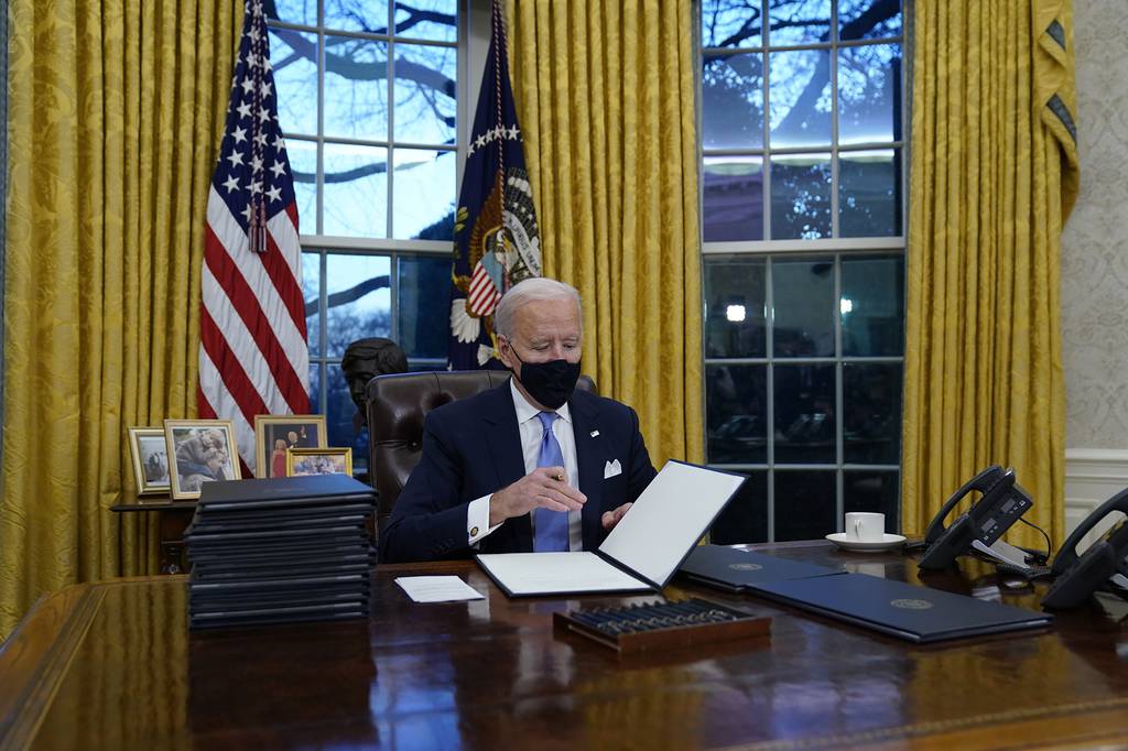 President Joe Biden signs his first executive orders in the Oval Office of the White House on Wednesday, Jan. 20, 2021, in Washington.