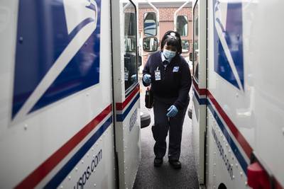 In this May 6, 2020, photo, United States Postal Service carrier Henrietta Dixon gets into her truck to deliver mail in Philadelphia.