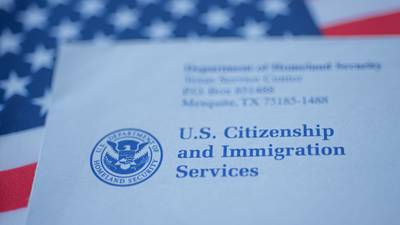 A U.S. Citizenship and Immigration Services envelope rests on an American flag.