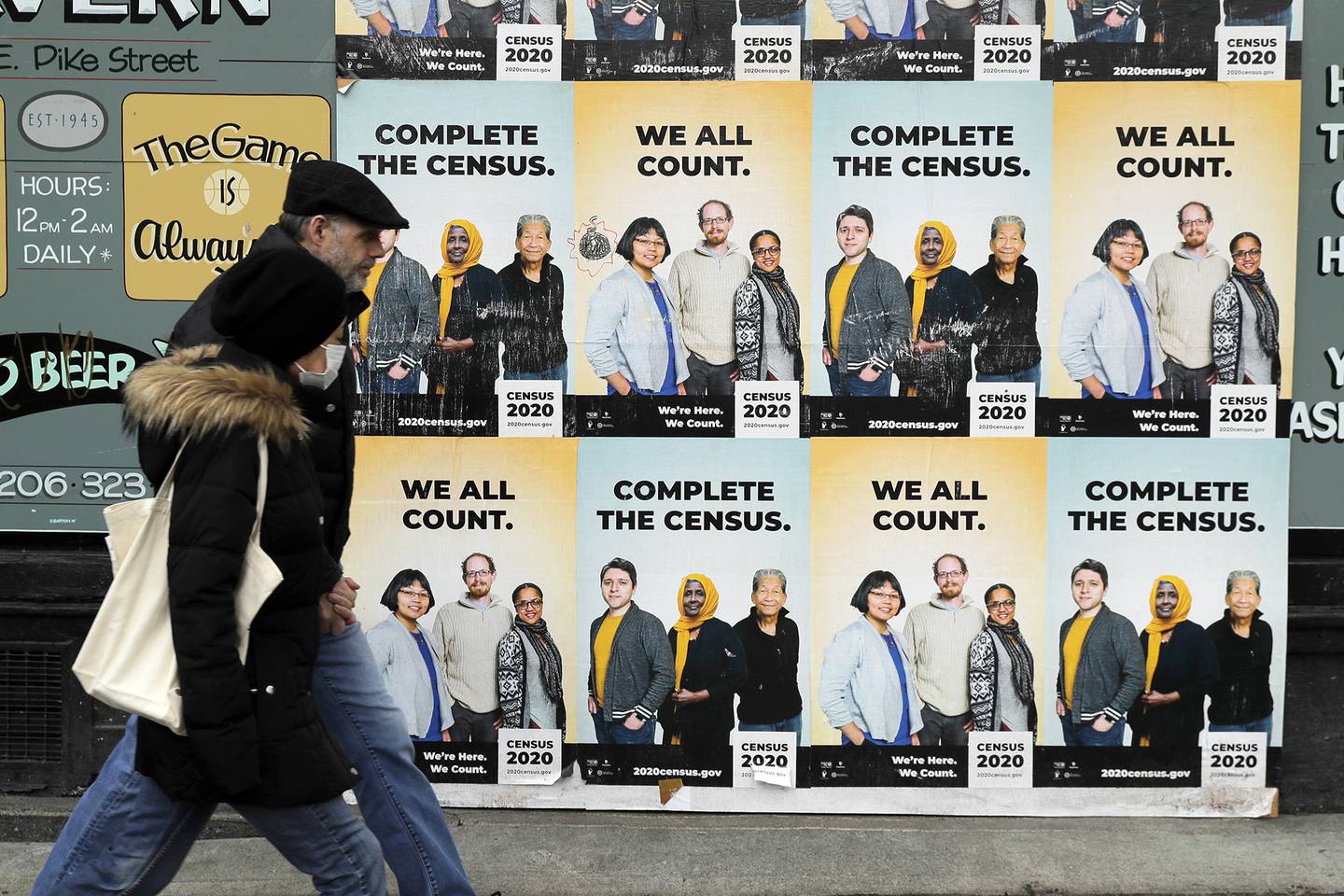 In this April 1, 2020, file photo, people walk past posters encouraging participation in the 2020 Census in Seattle's Capitol Hill neighborhood.