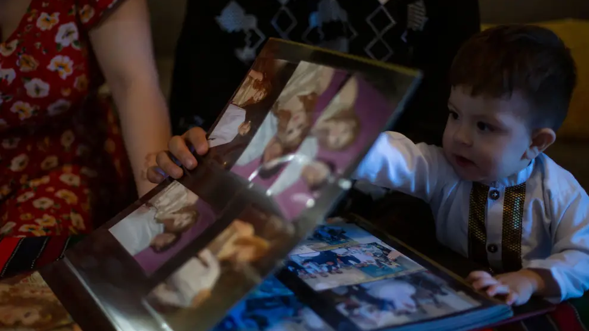 At their home in Austin, Azita Jawady, her husband Hamid Sadra and their 1-year-old son Qmars look through wedding photos from Afghanistan.